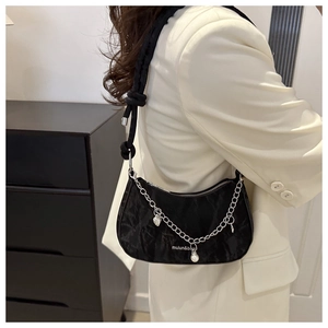 Détail du sac sous le bras en jacquard noir avec breloque perle et chaîne en métal