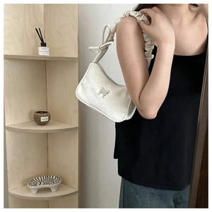 Close-up of cream white hobo bag with silver butterfly charm and pleated bow strap detail