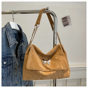 Detailed close-up of caramel PU leather messenger bag with silver butterfly buckle and chain