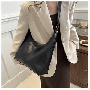 Detail of a black crescent shoulder bag with golden hardware and adjustable leather strap