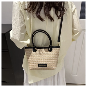 Detailed close-up of woven straw texture and black leather handles on a chic tote bag