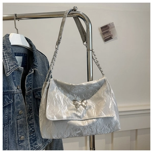Macro view of silver pleated texture and metallic butterfly clasp on stylish PU shoulder bag