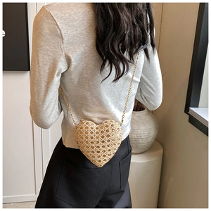 Detail of heart-shaped woven crossbody bag with amber crystals and gold chain strap