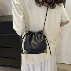 Fashionable black drawstring bucket bag with gold accents and leather chain shoulder strap