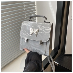 Detail of silver metallic butterfly backpack with textured leather and metal clasps