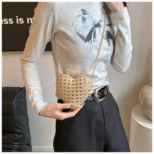 Detail of a gold heart-shaped clutch bag with sparkling rhinestones and a metal chain