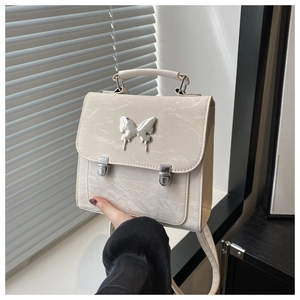 Detail of a creamy white textured leather handbag with a silver butterfly buckle clasp
