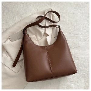 Detail view of large dark brown leather tote bag with adjustable strap and gold hardware