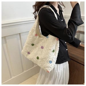 Détail du sac cabas blanc avec broderies florales colorées et texture en tissu tweed