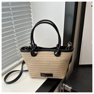 Close-up of beige woven straw bucket bag with black leather handles and fashion logo