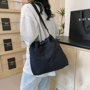 Minimalist black nylon drawstring shoulder bag with large capacity and adjustable strap
