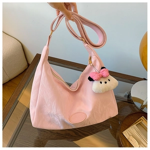 Detailed view of pink pleated nylon tote bag with plush charm and brand logo imprint