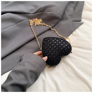 Detail shot of heart-shaped mini bag featuring black glitter finish and gold chain