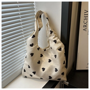 Détail d'un sac cabas beige avec imprimés cœurs noirs et texture soyeuse délicate