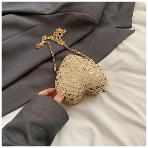 Detail of a gold heart-shaped evening bag featuring glittering sequins and a slim chain strap