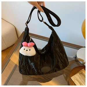 Detail of black pleated tote bag with a cute plush bunny charm and shoulder strap