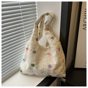 Détail d'un sac cabas en peluche blanche avec broderies colorées et texture douce