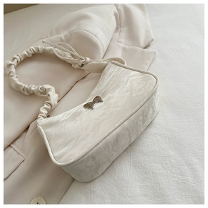 Dettaglio borsa a tracolla plissettata beige con fibbia a fiocco argentata