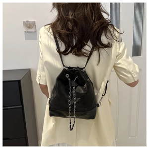 Detail of black bucket backpack with chain drawstring and FASHION & BAGS slogan print