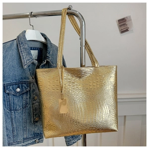 Close-up of golden crocodile pattern tote bag hanging on a minimalist metal rack