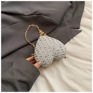 Macro shot of silver rhinestone heart clutch bag with gold chain and metal clasp