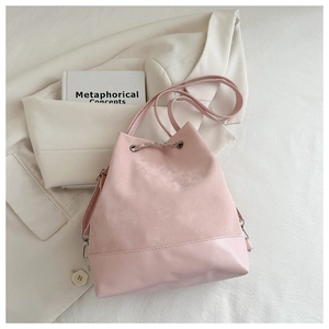 Pink drawstring bucket bag detail with mixed textures and metal chain on a blazer