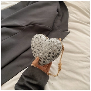 Macro detail of heart-shaped evening clutch with sparkling rhinestones and gold chain