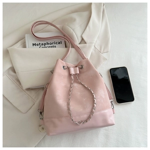 Chic pink bucket bag detail with metal chain and leather strap on white blazer