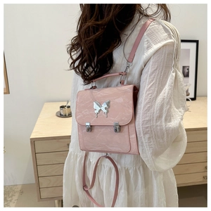 Macro view of a light pink mini backpack with silver metal butterfly and marble texture