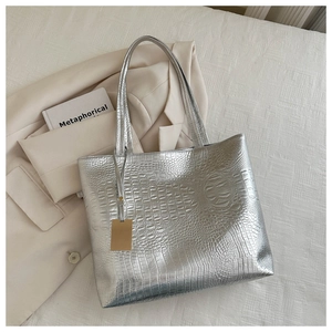 Detail of silver crocodile pattern tote bag showing metallic texture and handle craftsmanship