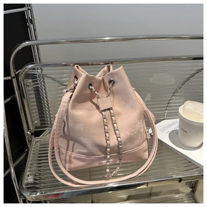 Pink drawstring bucket bag with chain detail on a modern chrome stand with coffee cup