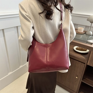 Vintage burgundy hobo tote bag worn by a model in a cozy, warm minimalist interior setting