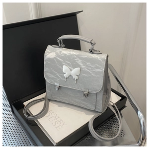 Detail of grey pleated faux leather backpack with white 3D butterfly and silver buckles