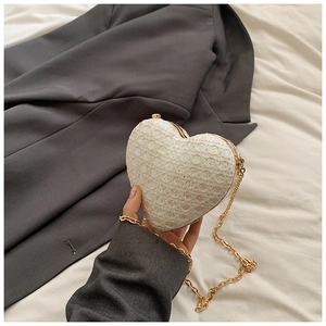 Macro view of heart-shaped evening bag with iridescent sequins and gold metal frame