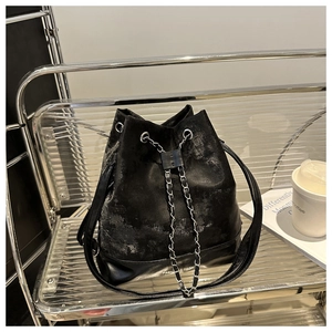 Close-up of black bucket bag with silver chain drawstring and fashion logo lettering
