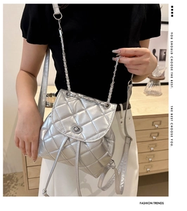 Detail view of silver quilted chain bucket bag with drawstring and turn-lock closure