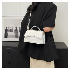 Détail du sac à main blanc minimaliste avec texture ondulée et fine bandoulière élégante