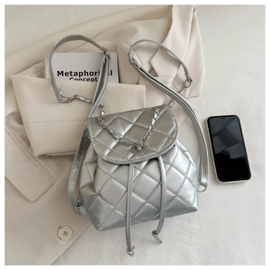 Detail of silver quilted backpack with metallic finish, chain straps and drawstring closure