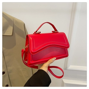 Détail d'un sac à main en cuir rouge vif avec des accessoires dorés et poignée