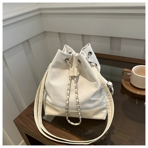 Detail of white bucket bag featuring silver chain drawstring and leather splicing texture