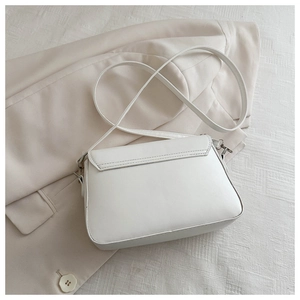 Detailed close-up of a white leather flap bag featuring an elegant metal adjustment buckle