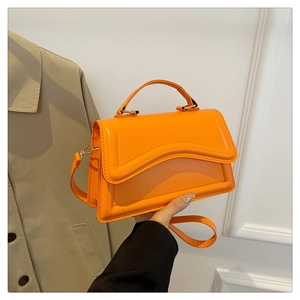 Détail d'un sac à main orange vif avec rabat ondulé et poignée supérieure élégante