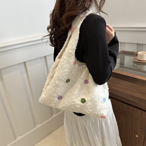 Sac cabas en peluche blanche avec motifs floraux colorés porté par un mannequin chic
