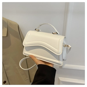 Détail d'un sac à bandoulière en cuir blanc minimaliste avec rabat à texture ondulée