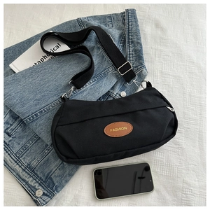 Detail view of black canvas crossbody bag with FASHION leather patch and metal zipper
