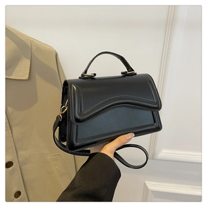 Détails du gaufrage ondulé et boucle en métal doré sur un sac à bandoulière en cuir noir