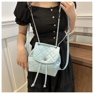 Close-up of baby blue quilted backpack with silver rotary lock and chain straps