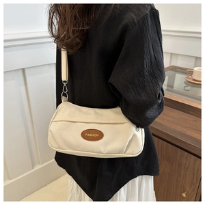 Close-up of beige canvas shoulder bag with adjustable strap and Fashion patch detail