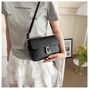 Detail of a black crossbody bag showing the silver U-shaped clasp and textured faux leather
