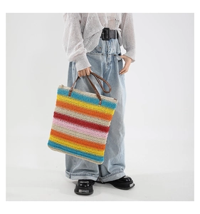 Detail of multi-colored striped straw woven tote bag with dark brown leather handles